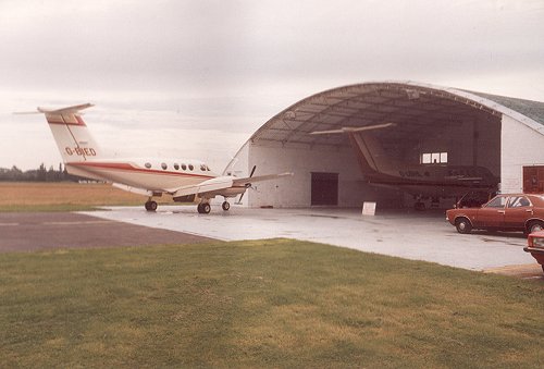 The brand new United Biscuits Beechcraft King Air F90, G-BIED, seen at the blister hangar facility in March 1981. Inside the hangar the new King Air Super 200B, G-UBHL, can be seen.