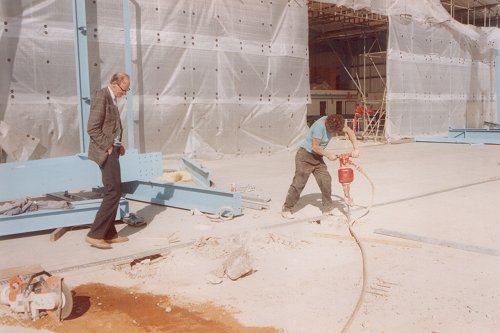 Ian Paul watches as the foundation holes for the new structure are drilled. The temporary front wall can be seen behind.